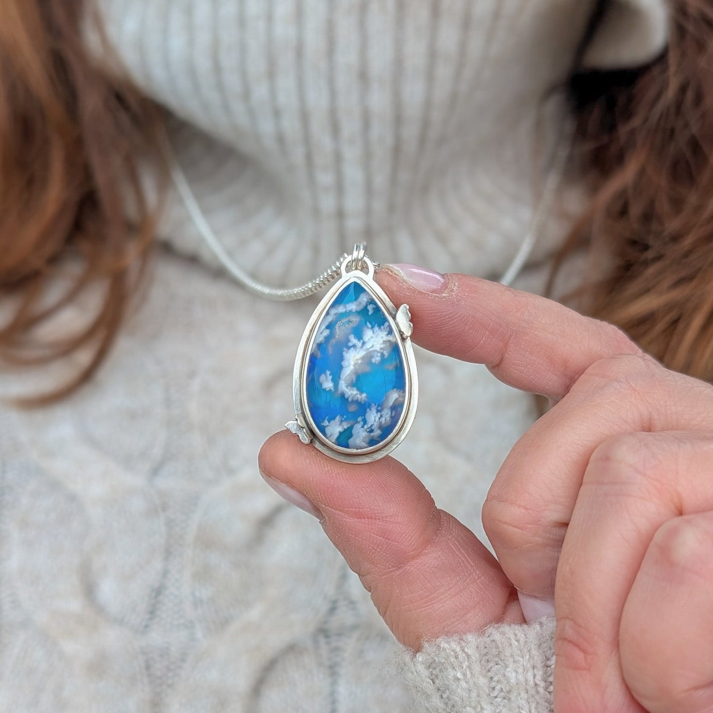 Colgante de plata y cielo con nubes